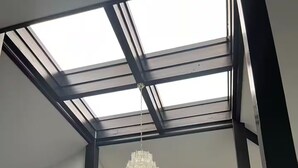 Une pièce dotée d’une lucarne, d’un lustre et d’un mur blanc avec une porte.