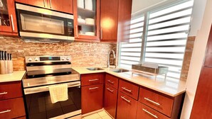 Una cocina con horno empotrado, microondas y pileta de acero inoxidable.