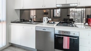 Una cocina moderna con alacenas blancas, lavavajillas, horno y estufa.