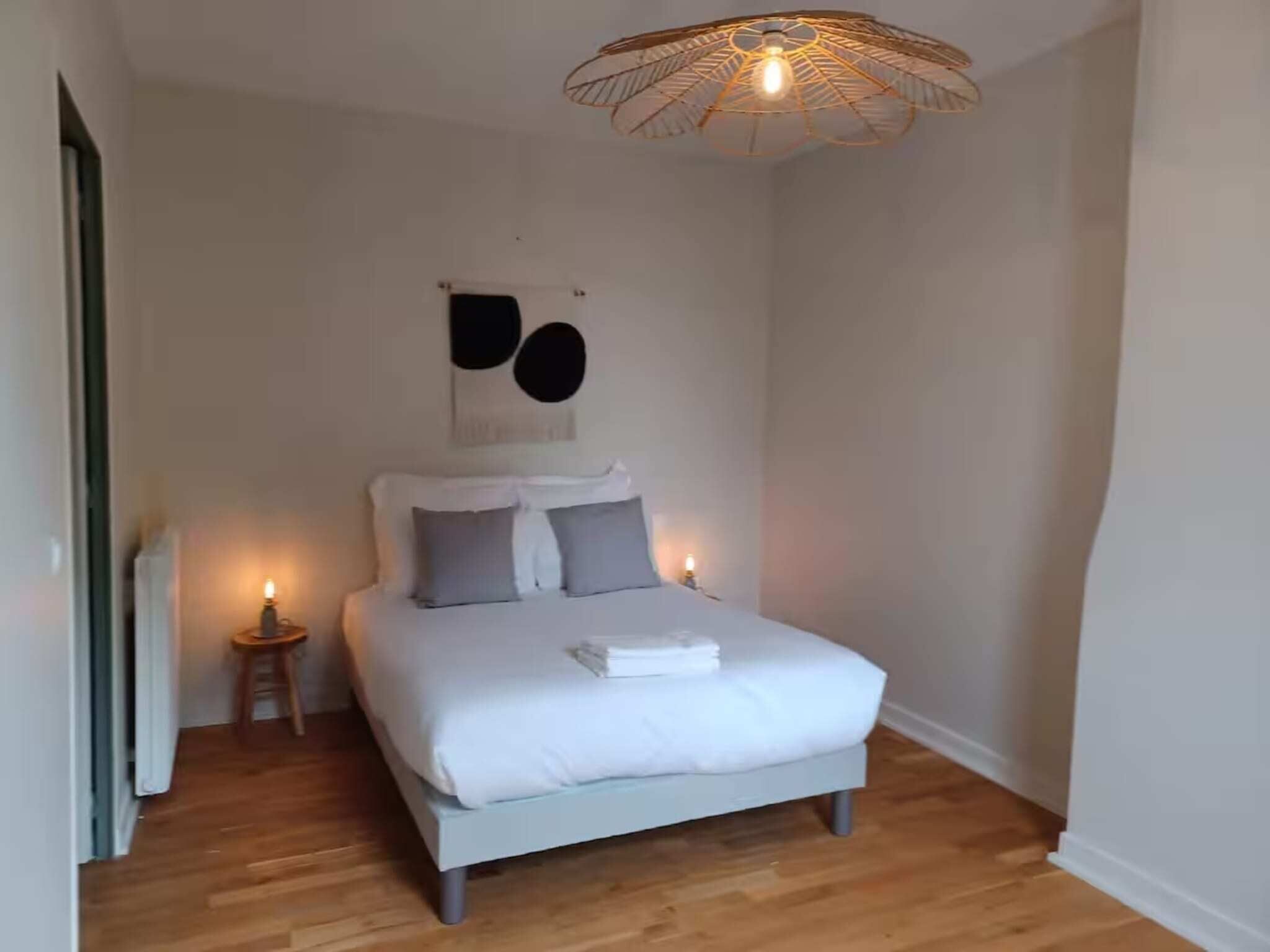 A bedroom with a bed, a bedside table, a wall-mounted light fixture, and a small wall decoration.
