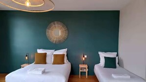 Une chambre d’hôtel avec deux lits, un miroir rond fixé au mur et un luminaire au plafond.