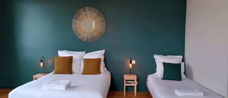 A hotel room with two beds, a round wall mirror, and a ceiling light fixture.