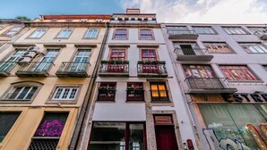 A multi-story building with balconies, a visible storefront, and a clear sky. - Central Apartments Stay Near Clérigos by HostWise (Porto)