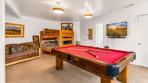 A room with a pool table, a sofa, and a bunk bed.