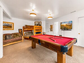 A room with a pool table, a sofa, and a bunk bed.