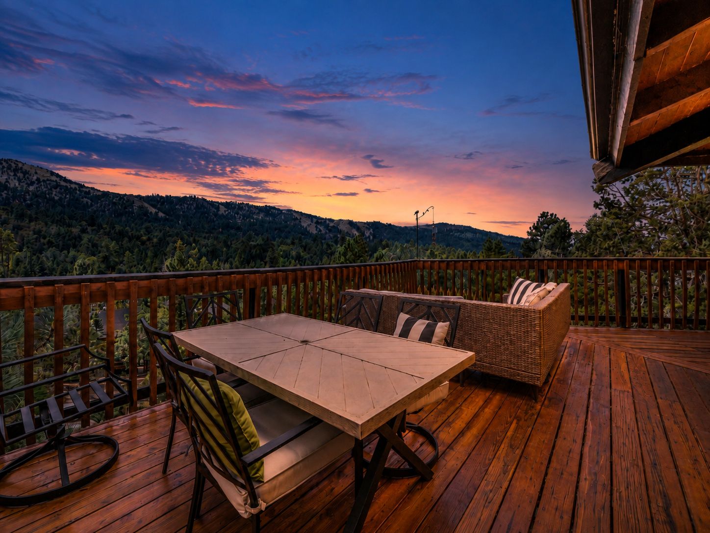 Une terrasse en bois avec une table et des chaises, donnant sur un paysage boisé.