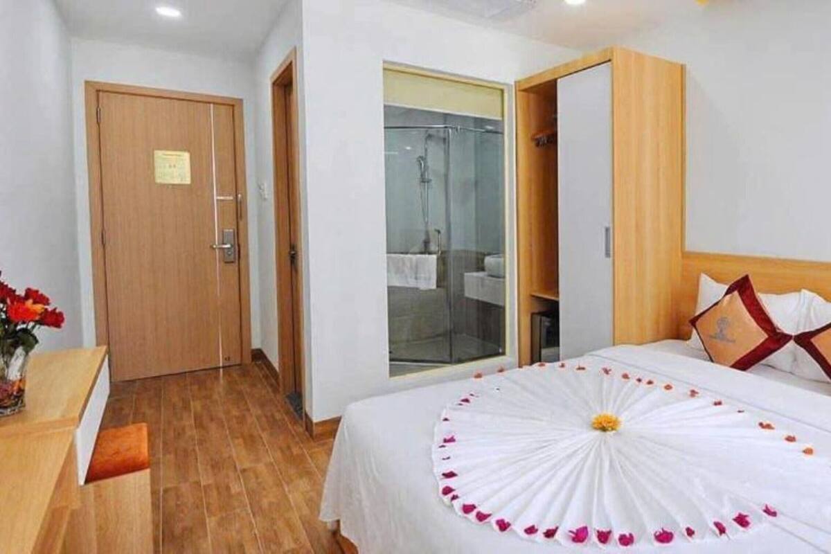 Una habitación de hotel con una cama, cabecero de madera y mampara de cristal para la ducha.