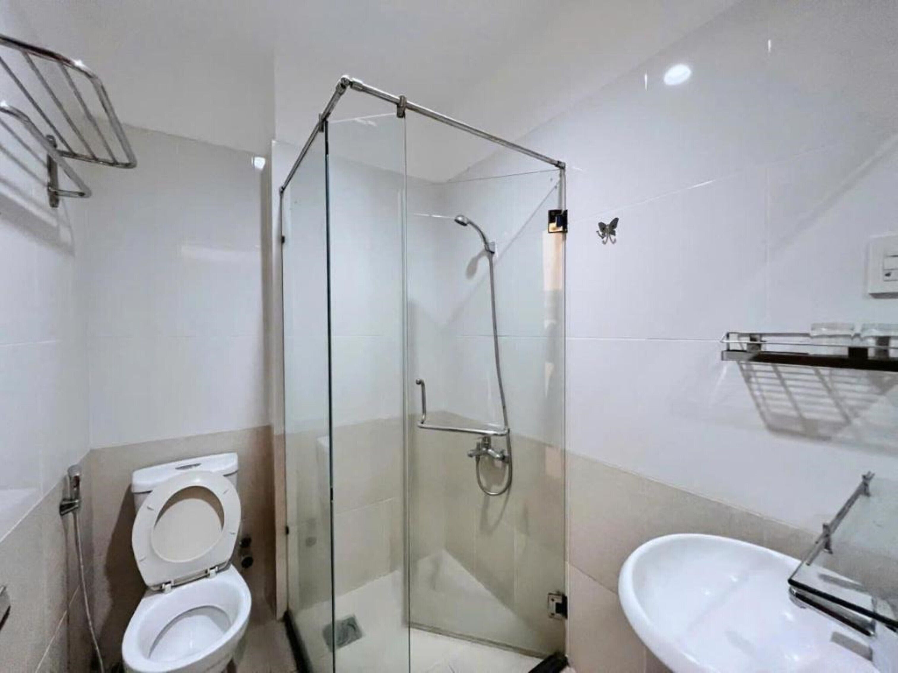 A modern bathroom with a glass-enclosed shower, a white toilet, and a sink with a mirror.
