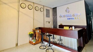 A hotel reception area with a wooden reception desk, multiple clocks on the wall, and a sign reading "Sophia & Sky Hotel". - Sophia Sky Hotel (Nha Trang)
