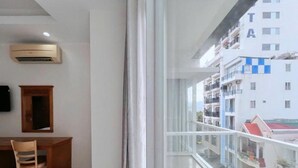 A modern apartment with a balcony, a wooden desk, and a mounted air conditioner. - Sophia Sky Hotel (Nha Trang)