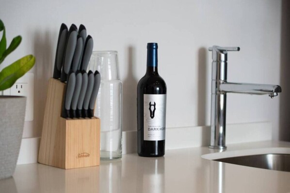 Una encimera de cocina con una botella de vino, un bloque de cuchillos y un grifo.