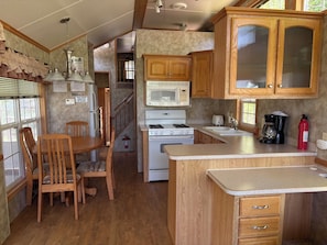 A compact kitchen with wooden cabinets, a microwave, a stove, and a sink.