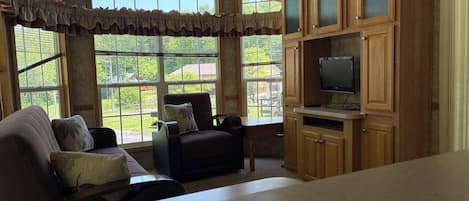 Una habitación con un ventanal grande, un sofá, una silla y armarios de madera.