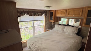 Un dormitorio con una cama grande, armarios de madera y una ventana con vistas a la vegetación.