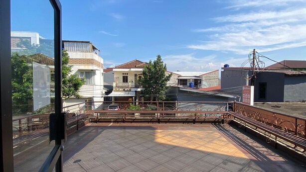 Eine Dachterrasse mit Fliesenboden, Metallgeländer und Blick auf die umliegenden Gebäude.