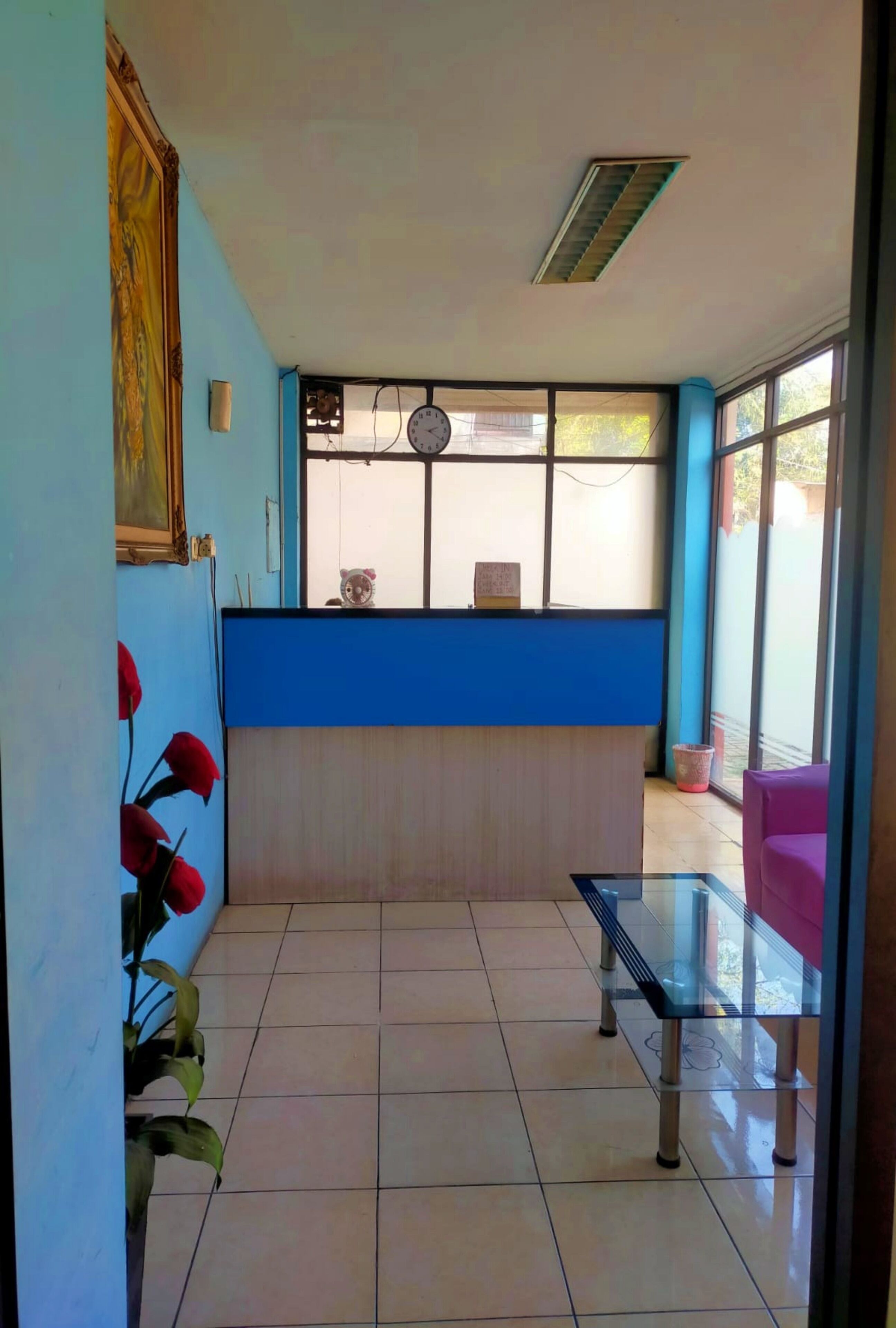 A reception area with a blue counter, a clock, and a window with a view.