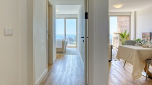 A modern hotel room with a balcony, a dining area, and a view of the cityscape. - The Place Funchal View, a Home in Madeira (Funchal)