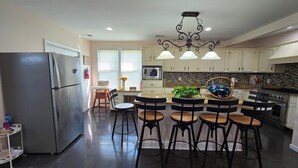 A modern kitchen with a central island, bar stools, a refrigerator, and a microwave.