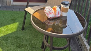 A balcony with a glass table, a chair, and a coffee cup.