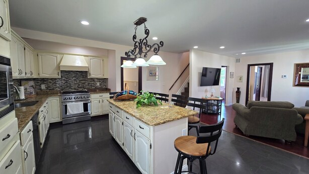 A modern kitchen with granite countertops, stainless steel appliances, and a central island with bar stools.