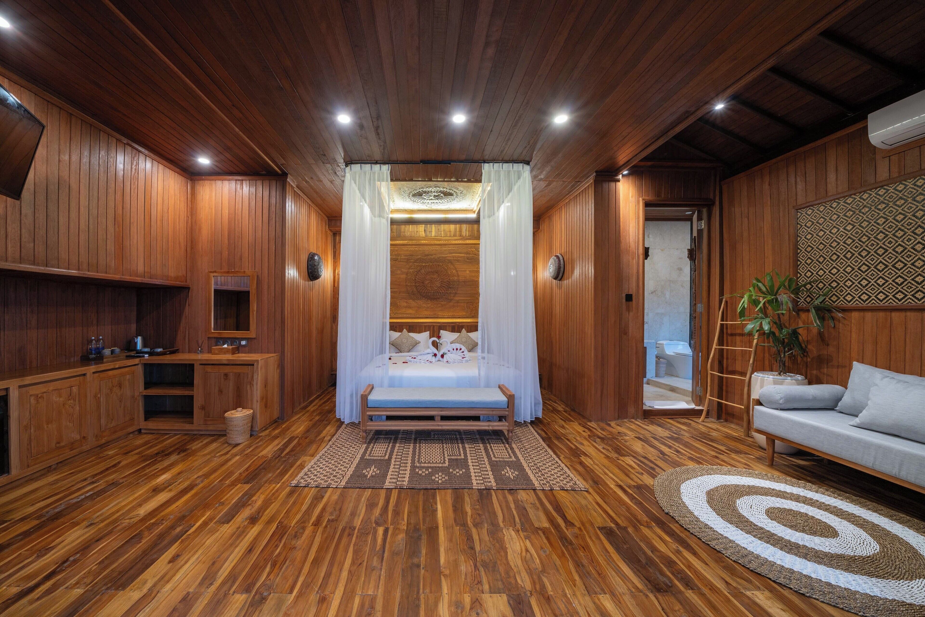 Een kamer met houten lambrisering, een bed, een bank en een kleine kitchenette.