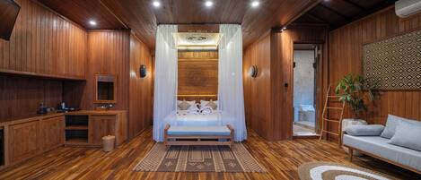 Een kamer met houten lambrisering, een bed, een bank en een kleine kitchenette.