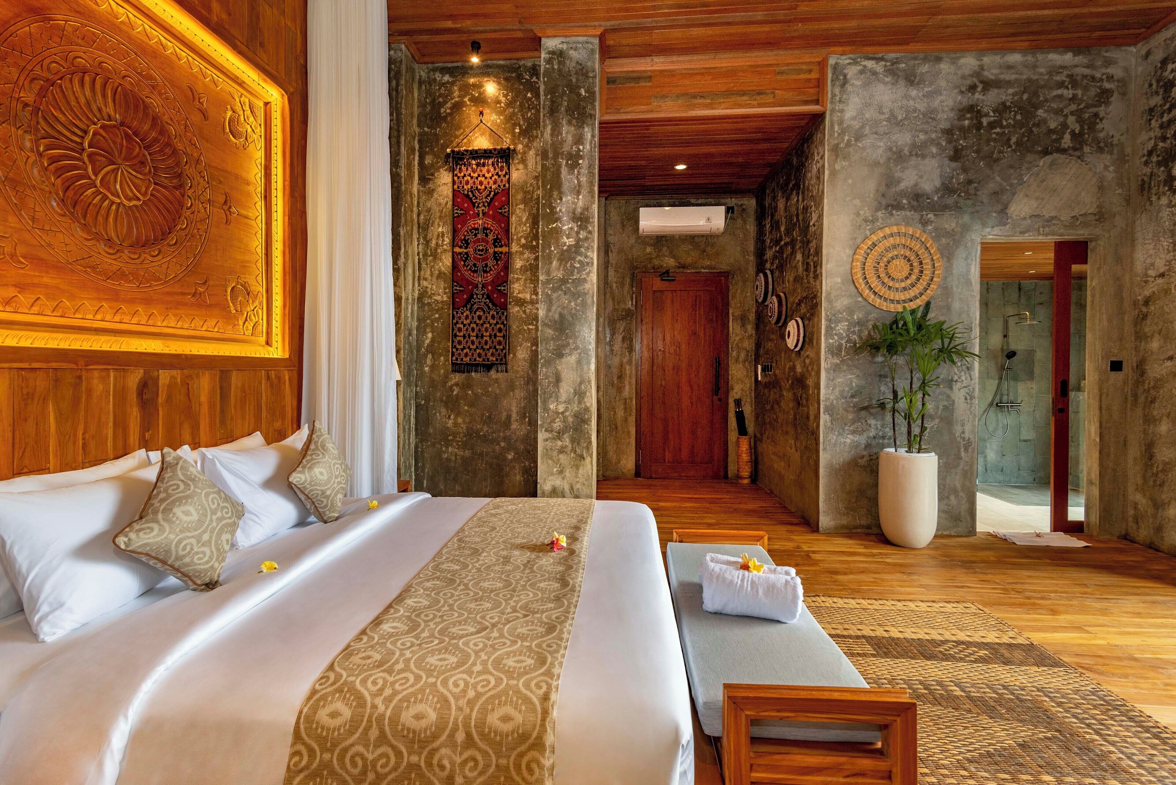 Une chambre d’hôtel spacieuse, dotée d’un grand lit, d’un plafond en bois et donnant sur le couloir.