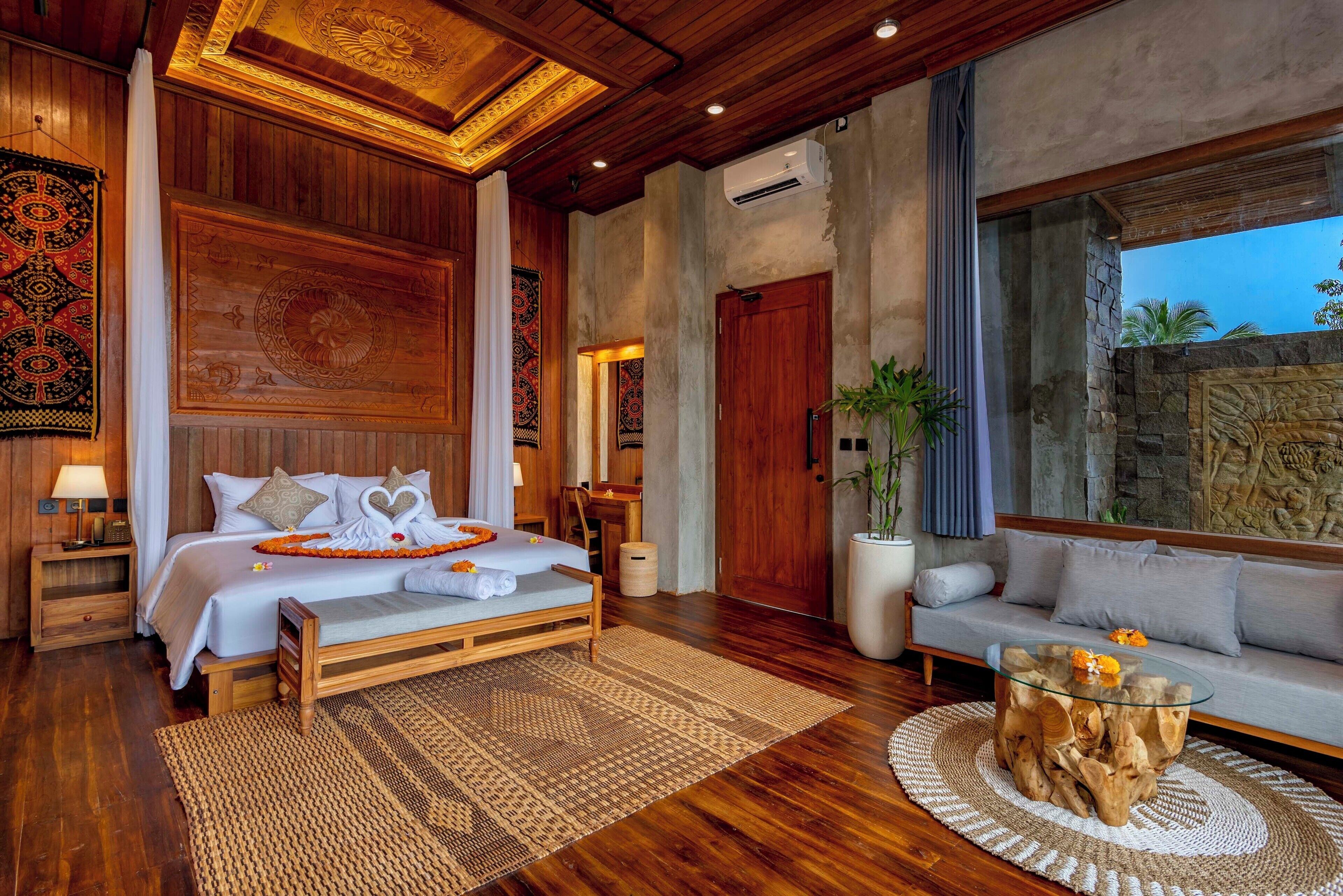 A spacious bedroom with a wooden bed, a glass coffee table, and a large window.