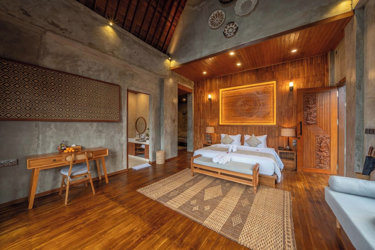 Um quarto amplo com cama de madeira, uma escrivaninha e uma cadeira.