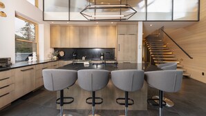 A modern kitchen with a central island, bar stools, and a staircase leading to an upper level. - Spectacular Views, Close to town, Mountain Modern elegance and entertaining! (Blue River)