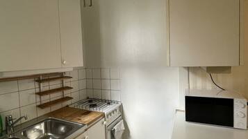 A kitchen with white cabinets, a stove, a microwave, and a wooden countertop.