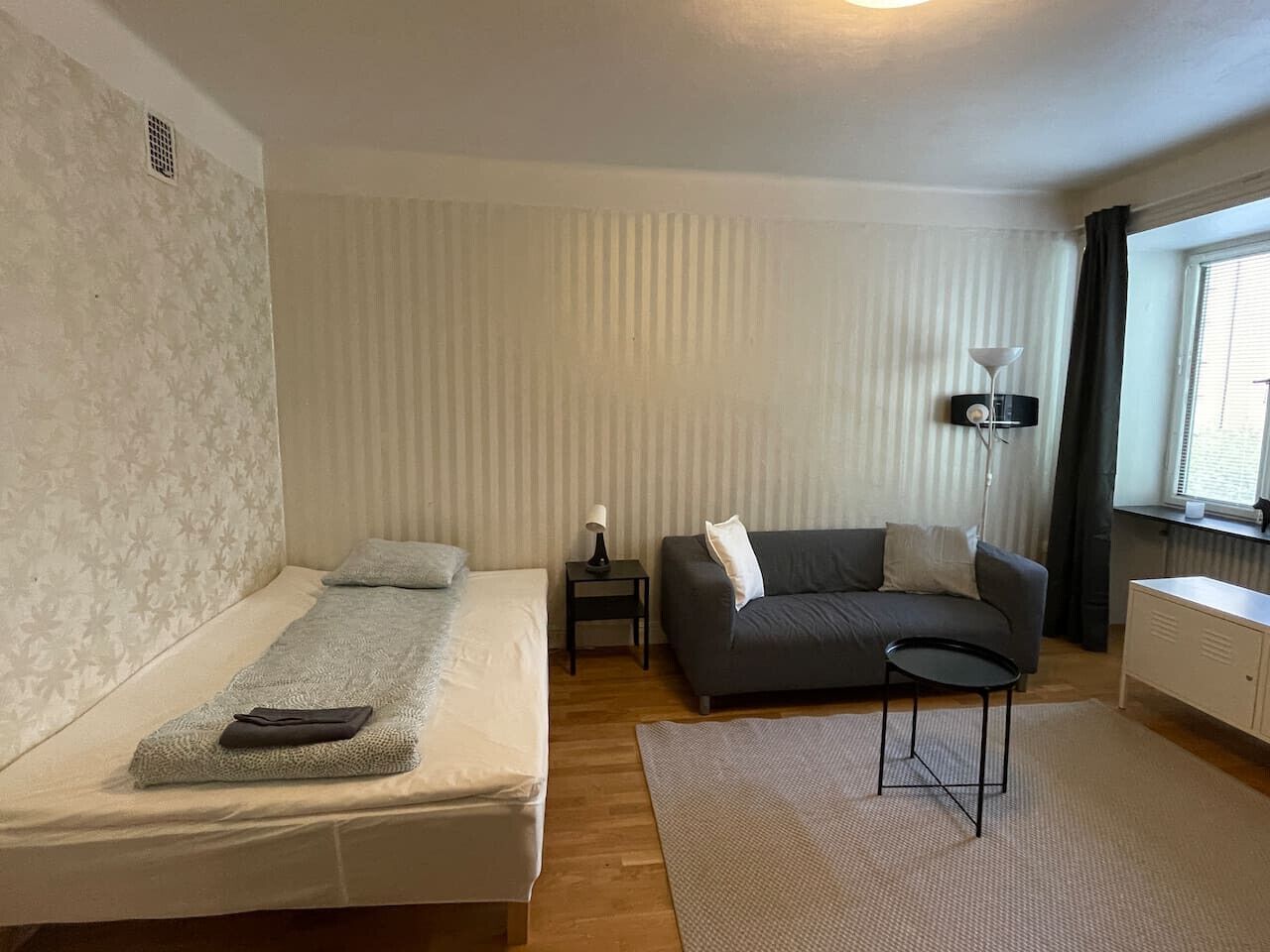 Ein Schlafzimmer mit einem Bett, einem Schlafsofa, einem kleinen Tisch und einer Lampe.