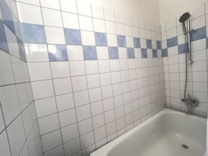 Ein Badezimmer mit weißen und blauen Fliesen, einer weißen Badewanne und einer Duschbrause.