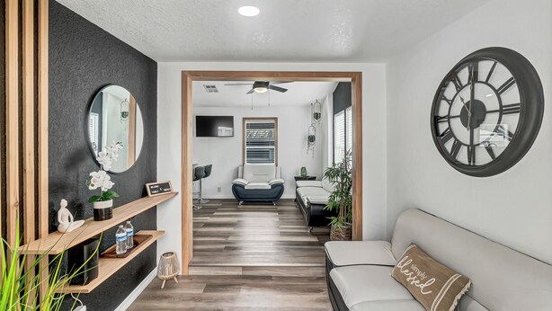 A modern living room with a sofa, a large wall clock, and a mirror. - Family-Friendly Cottage Near Orlando’s Top Attractions (Kissimmee)
