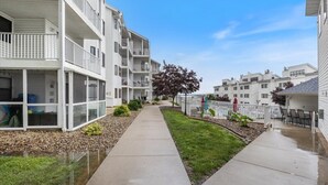 A residential building with multiple balconies, a covered walkway, and a small garden area.