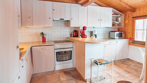 A kitchen with wooden cabinets, a stove, a microwave, and a sink.