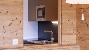 A modern kitchen with wooden paneling, a stainless steel sink, and a built-in microwave. - Christiania II S2 - 4 pers - près des pistes (Haute-Nendaz)