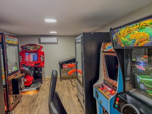 A row of arcade machines in a room with wooden flooring and a ceiling light. - Vintage Voyager on Black Lake (Hammond)