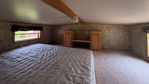 Une chambre à coucher avec un lit, des armoires en bois, une fenêtre et un ventilateur de plafond.