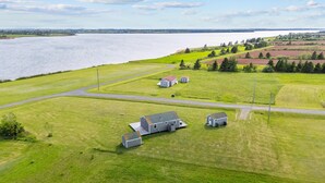 A rural landscape with a large body of water, a road, and several small buildings.