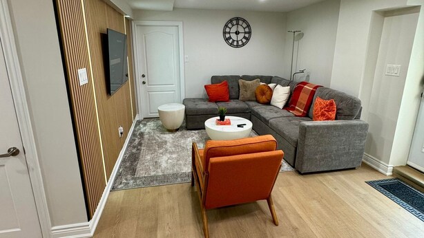 A modern living room with a grey sectional sofa, orange armchair, and a round coffee table.