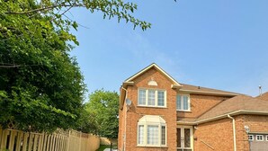 A two-story brick house with a front yard, a wooden fence, and a garage.