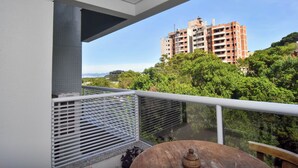 Un balcon donnant sur un immeuble et sur de la verdure.