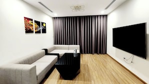 A modern room with a flat-screen TV, a sofa, a coffee table, and a projector screen.