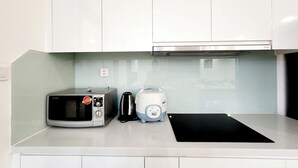 A kitchen with white cabinets, a microwave, a toaster, and a coffee maker on the countertop.