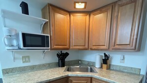 A kitchen with wooden cabinets, a microwave, a sink, and a coffee maker. - The C&C
Comfort and Convenience (Milwaukee)