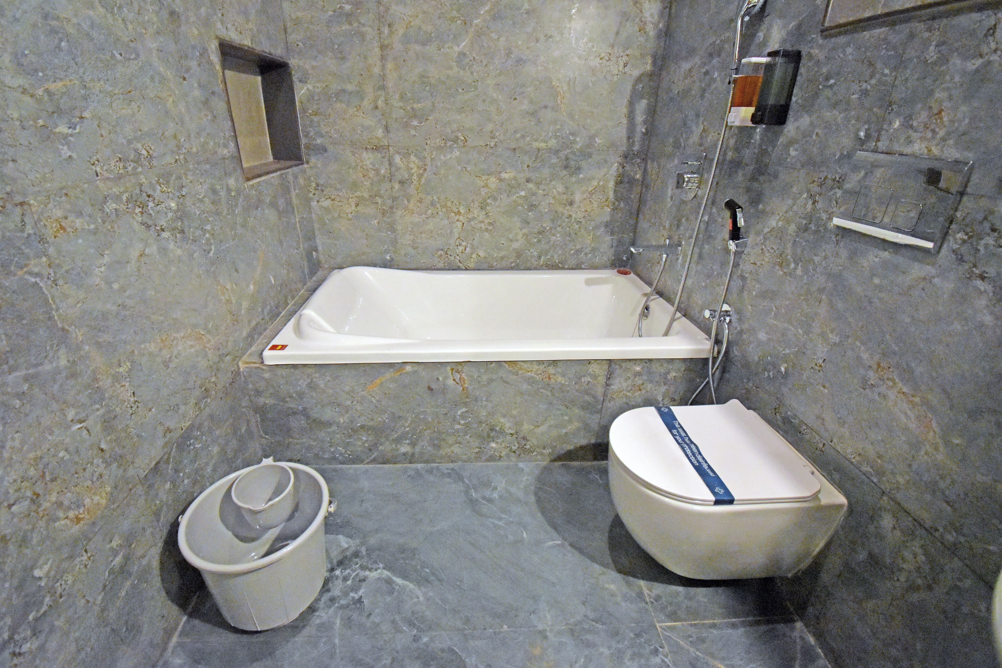 Ein Badezimmer mit einer Badewanne, einer Toilette und einem Eimer.