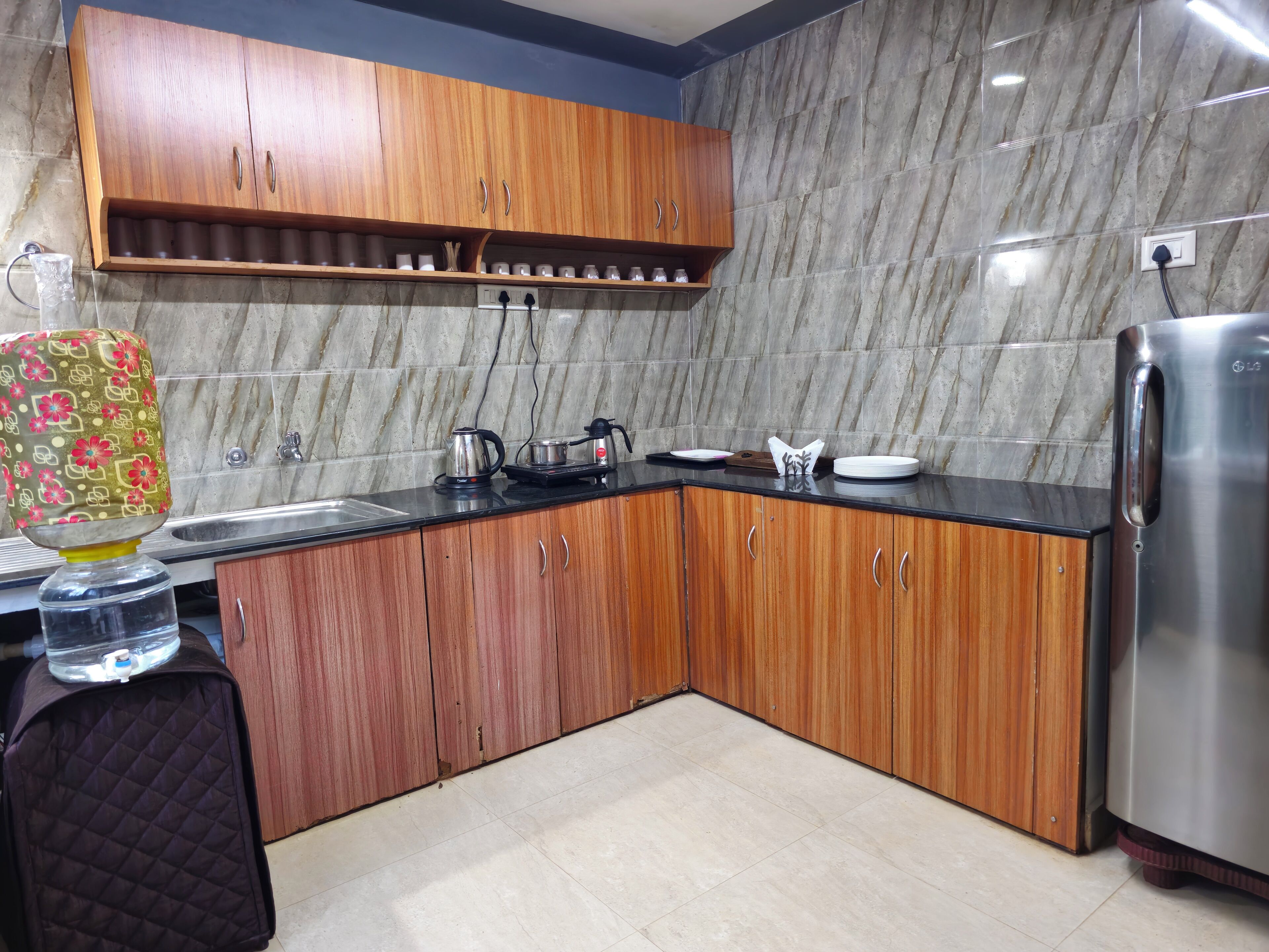 A kitchen with wooden cabinets, a stainless steel refrigerator, and a marble backsplash.