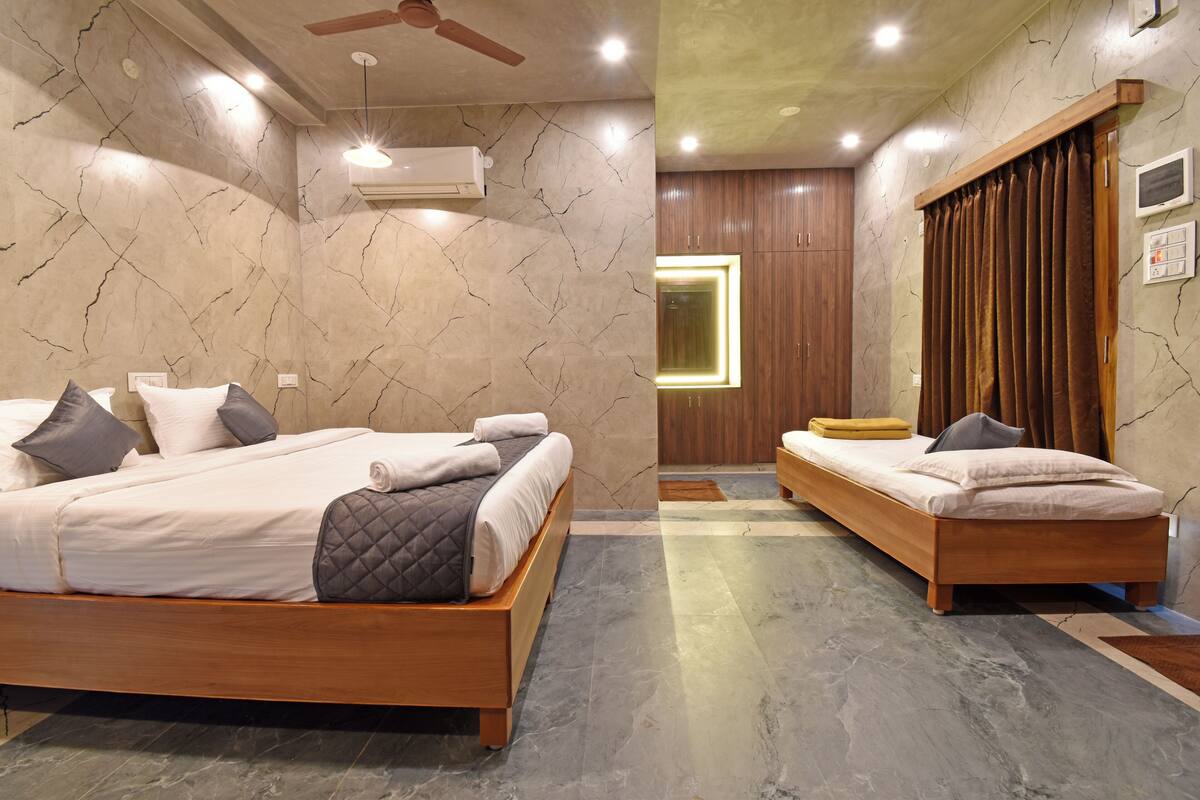 Une chambre moderne avec deux lits, des murs en marbre, des meubles en bois et un ventilateur de plafond.