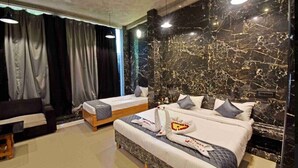Une chambre d’hôtel avec un mur en marbre, deux lits, un canapé et un bureau.